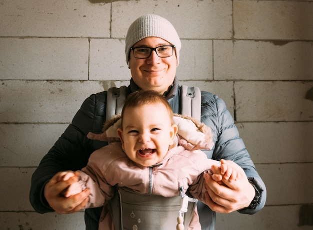 Papá y bebé felices en portador en casa nueva en etapa de renovación