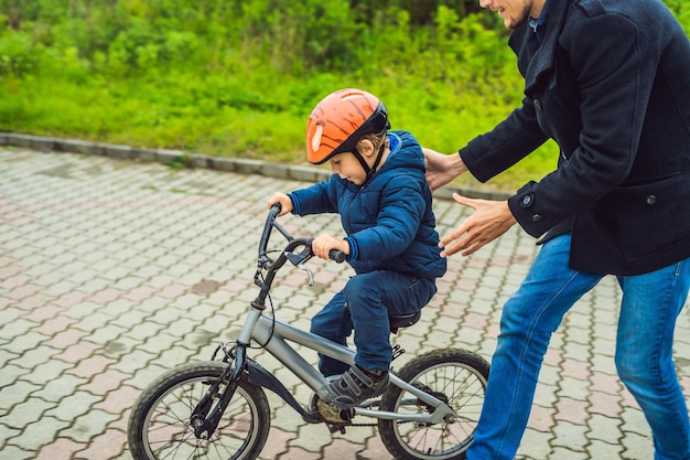 Papa bringt seinem Sohn das Fahrradfahren im Park bei.