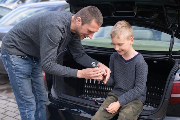 Papa bringt seinem süßen Sohn bei, ein Autoreparaturwerkzeug zu benutzen