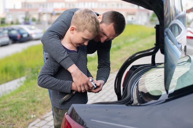 Papa bringt seinem süßen Sohn bei, ein Autoreparaturwerkzeug zu benutzen