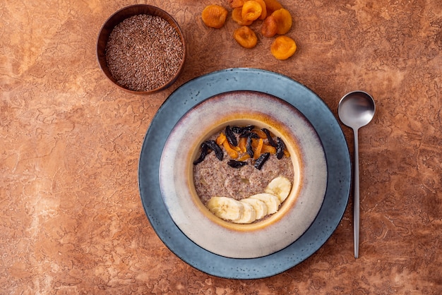 Papa de aveia do vegetariano do linho das sementes frescas com amêndoas e os abricós secados em um fundo claro. Fonte Omega 3.