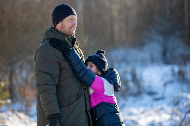 Papá e hija caminan en el parque de invierno