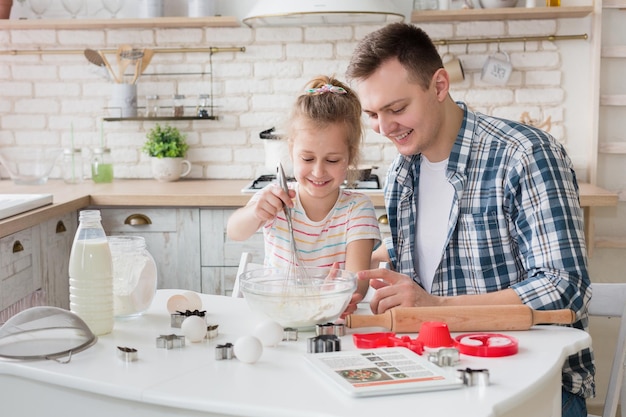 Papá e hija mezclando masa en un tazón, preparando galletas sorpresa para la madre, espacio de copia