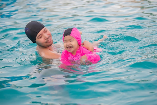 Papá e hija nadando en la piscinaGente de Tailandia