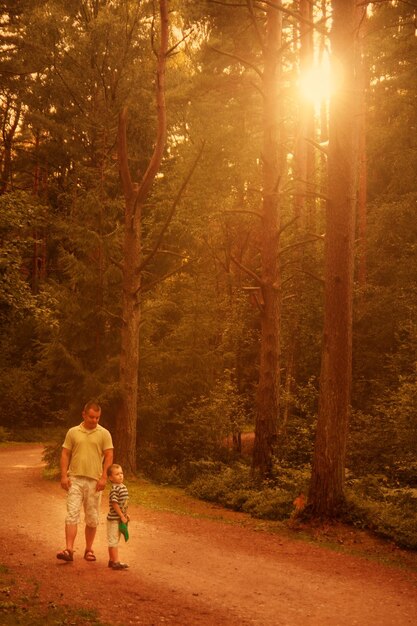 Papá e hijo caminando en el bosque al atardecer familia feliz al aire libre