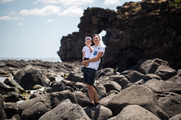 Papá e hijo caminando por la orilla del océano. Fin de semana en la playa. Una playa de piedra.