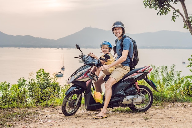 Papá e hijo en un ciclomotor contra un fondo de puesta de sol