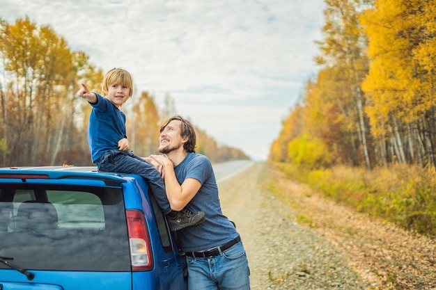 Papá e hijo descansan al costado de la carretera en un viaje por carretera. Concepto de viaje por carretera con niños.