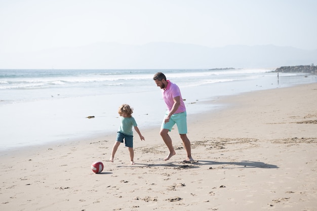 Papá e hijo se divierten al aire libre. infancia y crianza de los hijos. vacaciones en familia. actividad deportiva. padre e hijo juegan fútbol o fútbol en la playa. papá con niño niño en verano. fin de semana día familiar.