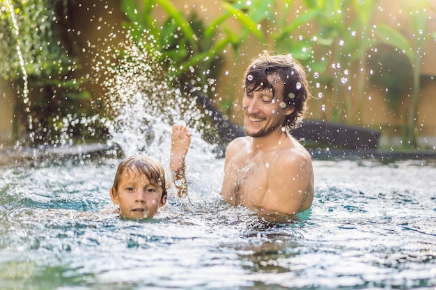 Papá e hijo se divierten en la piscina.