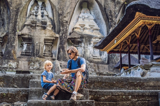 Papá e hijo en el fondo de Gunung Kawi. Antiguo tallado en el templo de piedra con tumbas reales. Bali, Indonesia. Viajar con el concepto de niños..