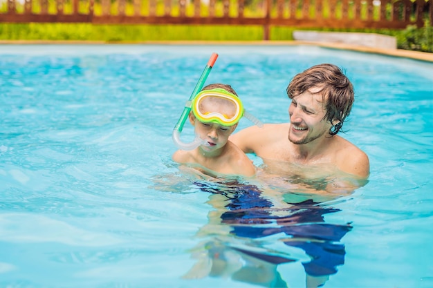 Papá e hijo en gafas de natación se divierten en la piscina