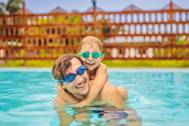 Papá e hijo en gafas de natación se divierten en la piscina