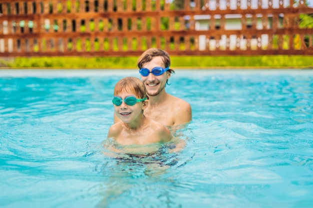 Papá e hijo en gafas de natación se divierten en la piscina