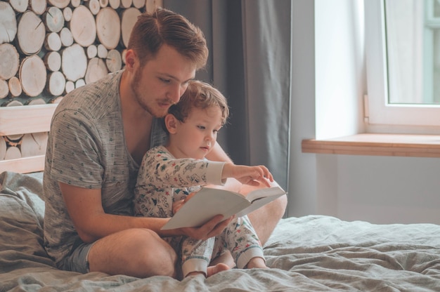 Papá e hijo leen un libro juntos, sonriendo y abrazándose