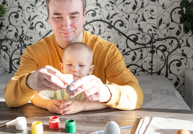 Papá e hijo pintan huevos para Pascua