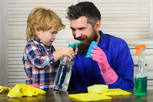 Papá e hijo con productos de limpieza. El padre se divierte con el niño y limpia la casa. El hombre acostumbra al niño a la limpieza.