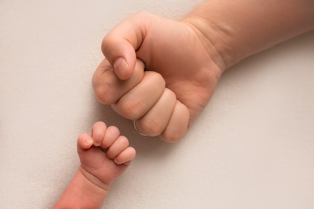 Papá e hijo recién nacido mantienen sus manos en un puño, puños pequeños y grandes. Padre e hijo, el primer puñetazo de boxeo. Foto de alta calidad