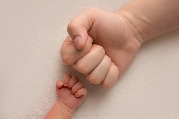 Foto papá e hijo recién nacido tomados de la mano juntos en la misma pose, puños grandes y pequeños, foto en blanco y negro. foto de alta calidad