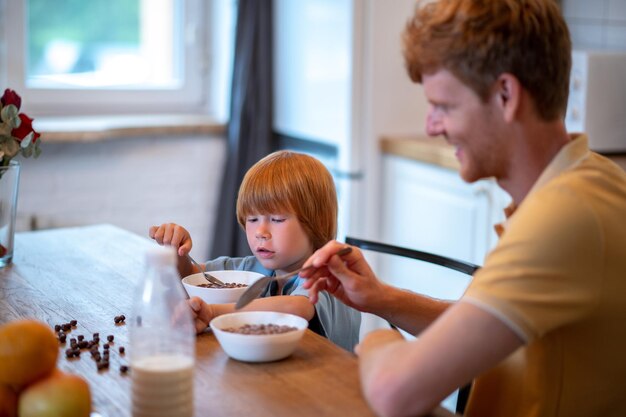 Papá e hijo sentados a la mesa y desayunando