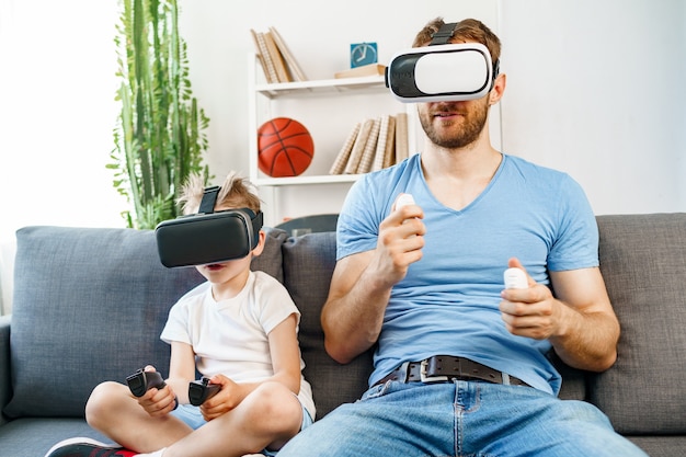 Papá e hijo sentados en el sofá y jugando con gafas VR