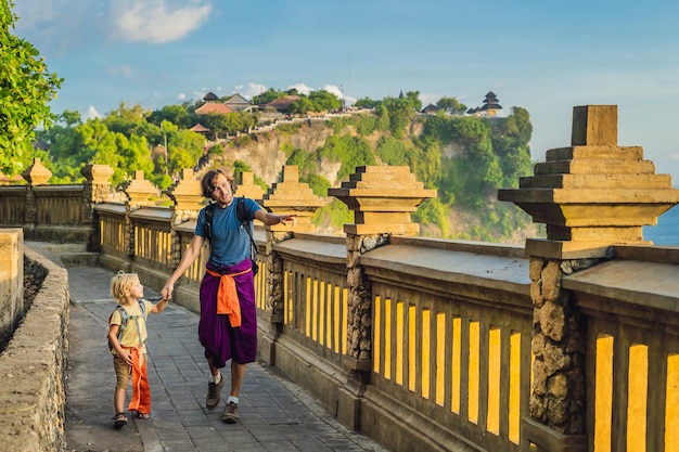 Papá e hijo viajeros en el templo Pura Luhur Uluwatu Bali Indonesia Increíble paisaje acantilado con cielo azul y mar Viajar con el concepto de niños