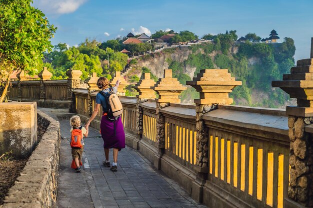 Papá e hijo viajeros en el templo Pura Luhur Uluwatu Bali Indonesia Increíble paisaje acantilado con cielo azul y mar Viajar con el concepto de niños