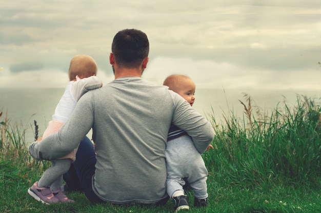 Papá le enseña a su hija a caminar, parque, naturaleza. Camina sobre la hierba. Padre e hija. Primeros pasos.