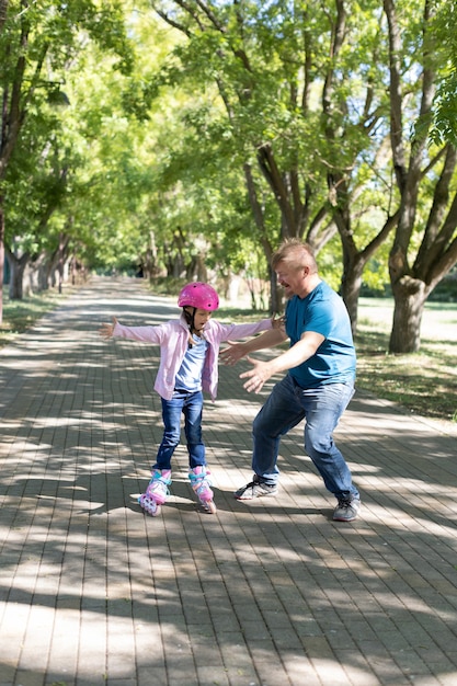 Papá enseña a su hija a patinar en el parque