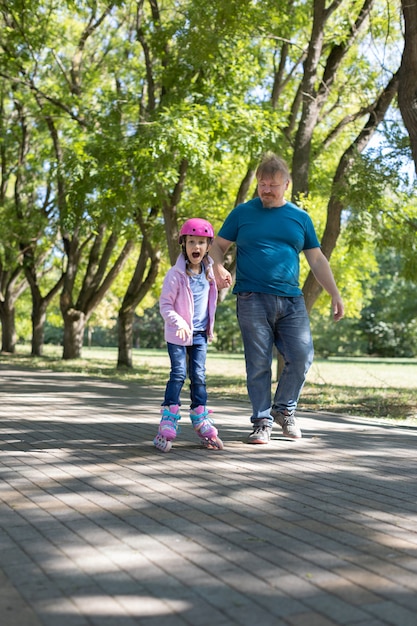 Papá enseña a su hija a patinar en el parque