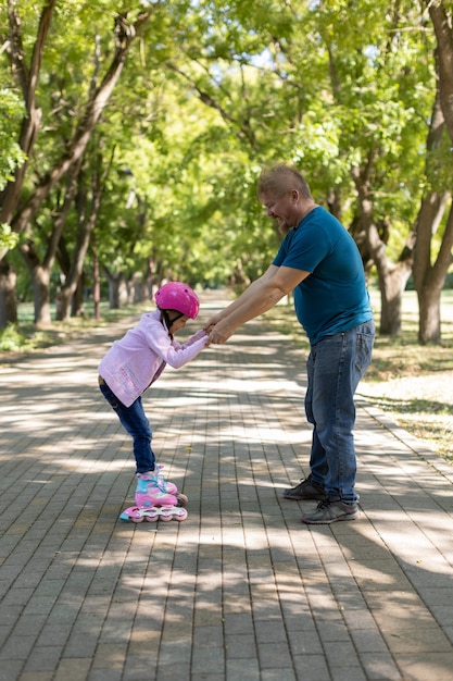 Papá enseña a su hija a patinar en el parque