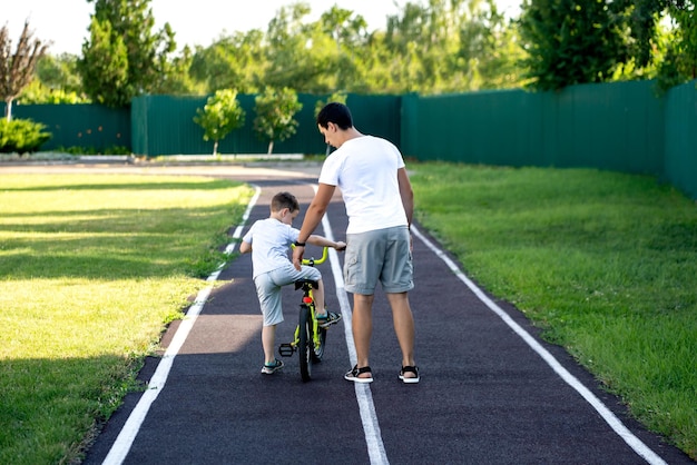 papá le enseña a su hijo a andar en bicicleta, estadio, concepto de vacaciones familiares