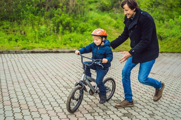 Papá le enseña a su hijo a andar en bicicleta en el parque