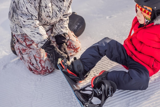 Papá enseña a su hijo a hacer snowboard Actividades para niños en invierno Deporte de invierno para niños Estilo de vida