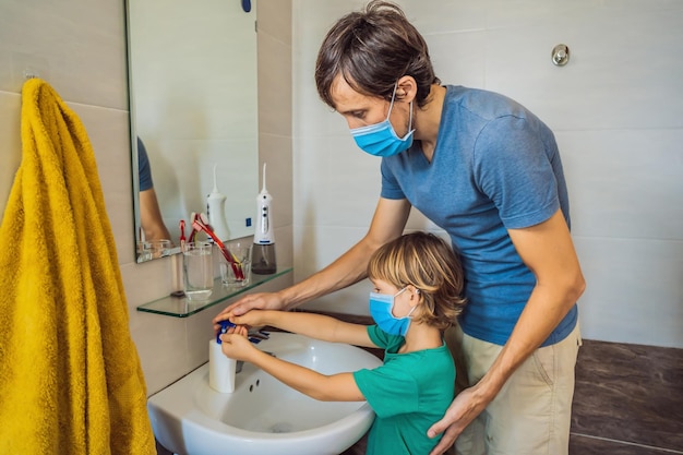 Papá le enseña a su hijo a lavarse las manos correctamente Papá e hijo con máscaras médicas debido a la epidemia de coronovirus Quédate en casa Lávate las manos