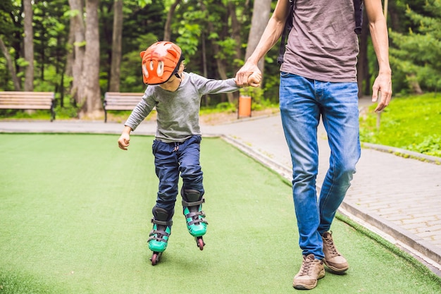 Papá le enseña a su hijo a patinar en el parque