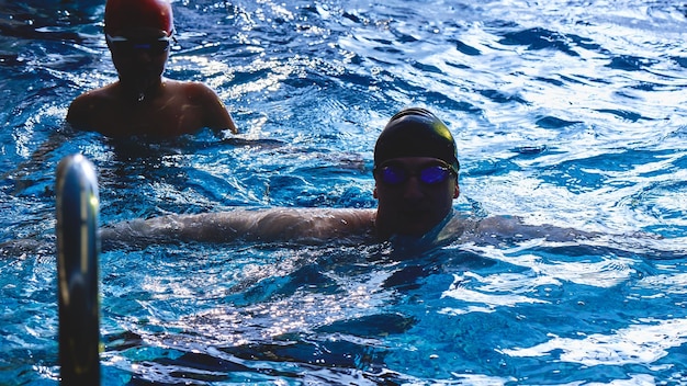 Papá y entrenador le enseñan a su hijo a nadar, divertirse, jugar y chapotear en una piscina azul