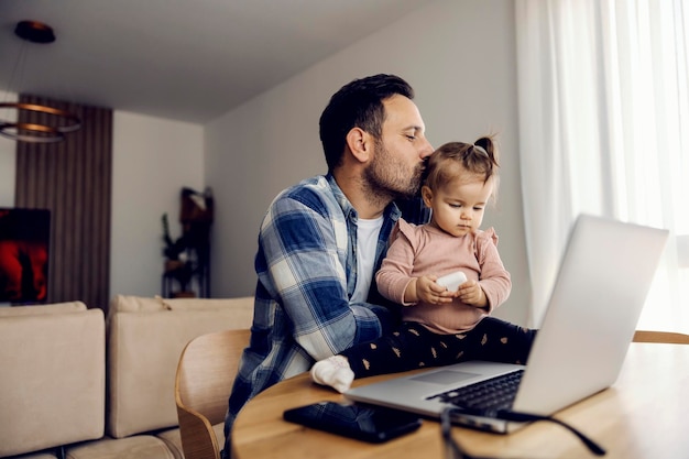 Papá está besando a su amada hija en un descanso del trabajo remoto