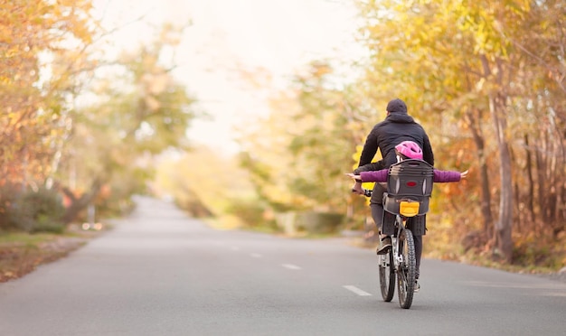 Papa fährt mit seinen Kindern Fahrrad auf einer Herbststraße