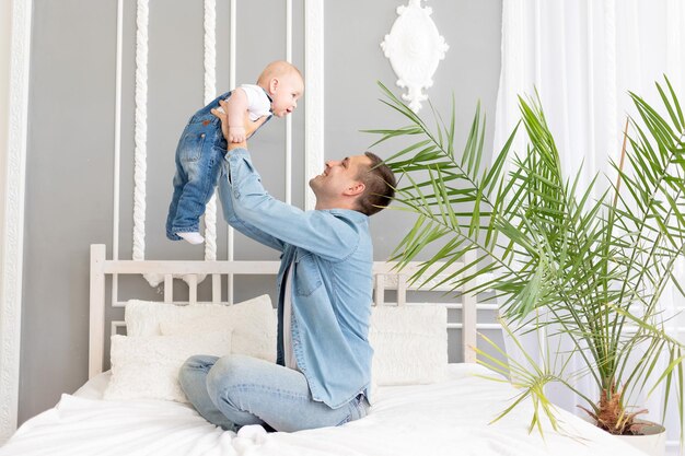 Papá de familia feliz jugando con el bebé en casa en el concepto del día del padre de la cama o paternidad feliz