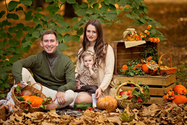 Papá de familia feliz, mamá, hija en el picnic de otoño con calabaza y manzanas