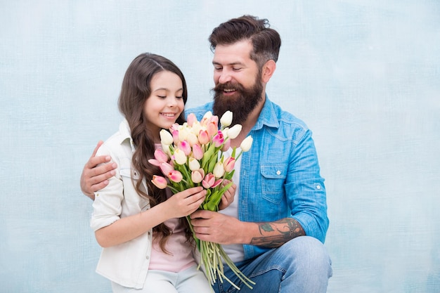 Papá felicita a la niña pequeña de vacaciones y le da flores el día de la familia pasando tiempo juntos hija toma un ramo de flores de tulipán feliz padre recibió un regalo el día del padre 8 de marzo Día Internacional de la Mujer