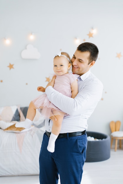 Papá feliz joven sostiene a su hija sonriente en sus brazos