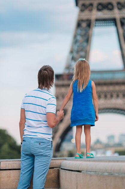 Papá feliz y niña adorable viajando en París cerca de la Torre Eiffel