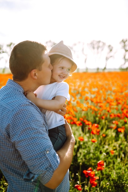 Papá feliz y niña divirtiéndose en el campo de amapola floreciente Besos de padre e hija
