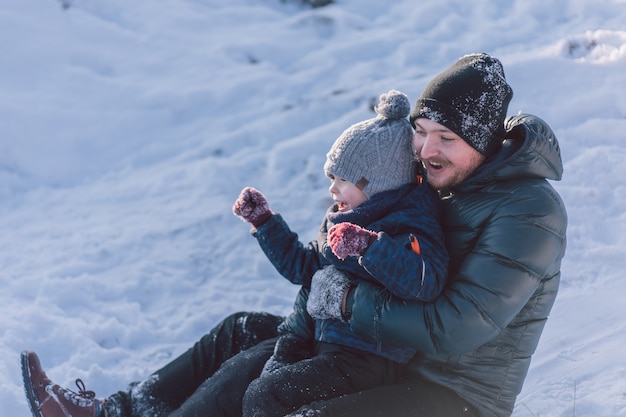 Papá feliz y niño jugando con trineo de nieve