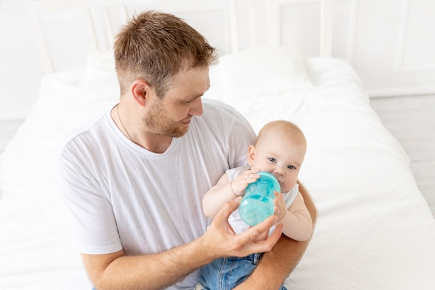 Papa füttert Babysohn aus einer Flasche zu Hause, glückliche Vaterschaft, Babynahrungskonzept
