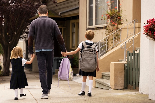 Foto papa geht mit kindern zum ersten schultag