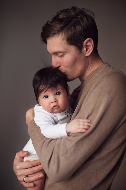 Foto papa hält seinen kleinen sohn in den armen und küsst seinen kopf