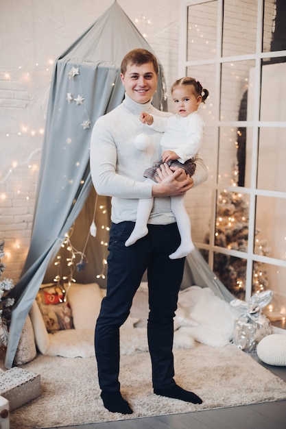Papá con hija en Navidad interior. Padre con su pequeña hija encantadora en brazos.